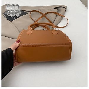 Close-up of caramel brown lychee texture leather handbag with dual handles and gold hardware