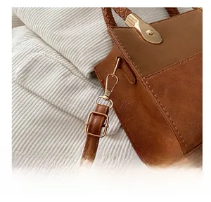 Detail of gold metal hook and woven handle on brown textured PU leather handbag