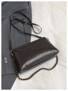 Détail de la texture cuir huilé marron foncé sur un petit sac bandoulière vintage