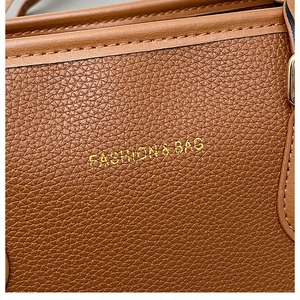 Close-up of brown litchi grain leather bag with gold Fashion & Bag lettering and fine stitching