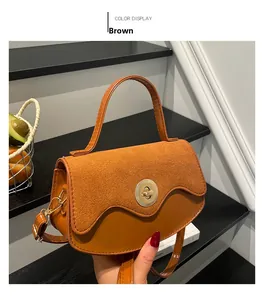 Detailed shot of brown leather handbag with suede flap and golden twist lock closure