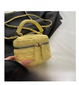 Detail of yellow quilted leather mini bag with double zippers and gold chain strap