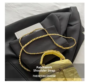 Close-up of bright yellow quilted mini bag with chain strap on a gray blazer