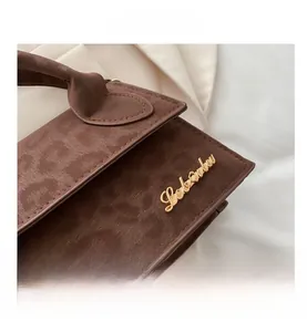 Gros plan d'un sac à main en daim marron avec logo doré et texture léopard subtile