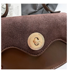 Detailed macro view of the vintage brown tote with suede texture and golden metal lock