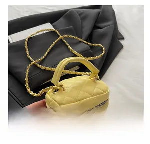 Macro view of yellow quilted leather vanity bag with gold chain and dual zippers