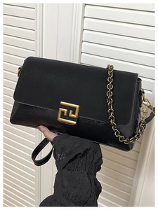 Détail du sac bandoulière noir avec boucle dorée géométrique et sangle en chaîne