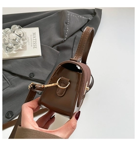 Detail view of the brown leather mini bag showing textured stitching and metal strap buckle