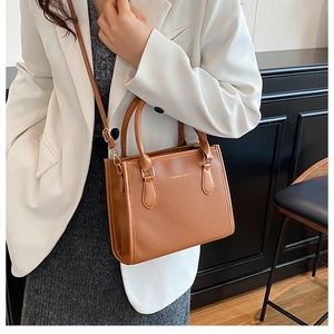 Close-up of caramel brown pebble leather handbag styled with elegant office wear