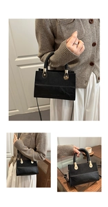 Detail of black crossbody bag showing textured leather stitching and gold hardware