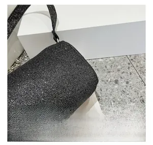 Dettaglio di tessuto glitterato nero con catena in metallo argentato su borsa trendy