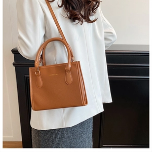 Close-up of brown lychee texture leather bag with elegant gold embossed fashion text