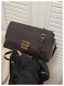 Détail d'un sac à bandoulière en cuir marron avec une boucle dorée géométrique