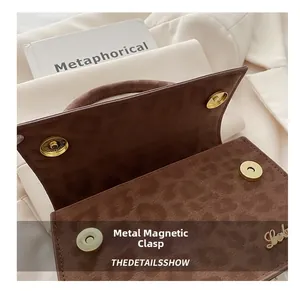 Détail de la fermeture magnétique et du logo doré sur un sac à main à motif léopard