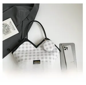 Detail view of grey plaid tote bag with round coin purse, tablet, and smartphone inside
