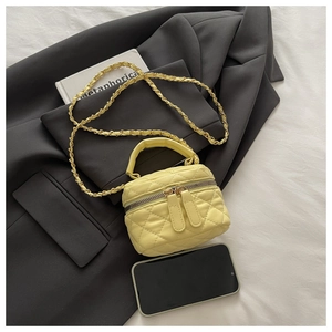 Macro detail of quilted yellow leather mini box bag with gold chain strap and dual zippers