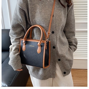 Detailed view of bicolor crossbody bag with black lychee texture and brown handle