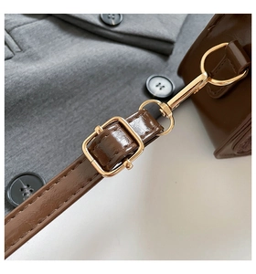 Detail of dark brown leather strap with adjustable shiny gold metal buckle and clasp