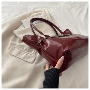 Close-up of a glossy deep red patent leather tote bag with elegant handles for women