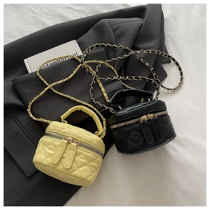 Detail of yellow and black quilted mini box bags with gold chain straps and top handles