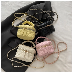Close-up of four colorful quilted mini bucket bags with gold chain straps on a black blazer