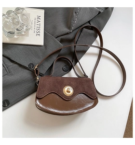Detail of a deep brown crossbody bag featuring suede patchwork and a gold twist lock
