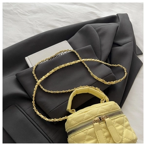 Close-up of yellow quilted mini bucket bag with chain strap and leather handle details