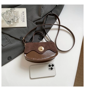 Detail shot of vintage brown leather handbag featuring gold circular twist lock and suede flap