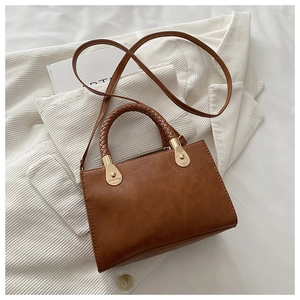 Detail of a brown vintage crossbody bag with a distinctive woven handle and gold hardware