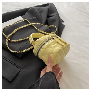 Macro shot of yellow quilted PU leather mini bag with gold chain and handle detail