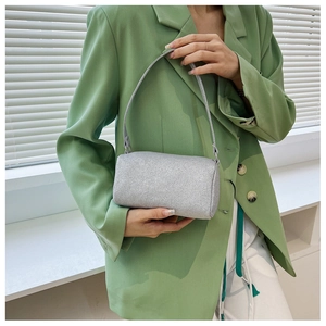 Primo piano di una borsa a cilindro argento glitterata portata con giacca verde