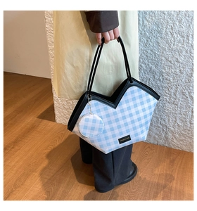 Detail of blue plaid tote bag with black handles and round coin purse charm