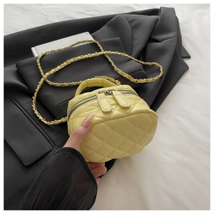 Detail of yellow quilted mini box bag with gold chain strap and dual zippers