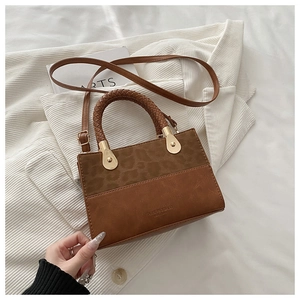Detail of a brown patchwork handbag with leopard pattern and braided handle on a suit