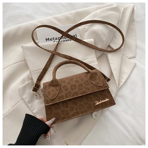Détail d'un sac à main léopard avec ferrures dorées sur un blazer blanc