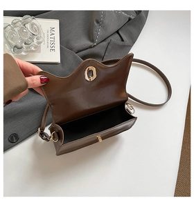 Detail of dark brown cat-ear flap bag with gold oval twist lock and spacious interior