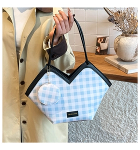 Detail of blue gingham tote bag with mini coin purse on a stylish beige trench coat