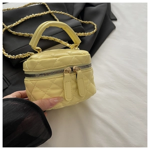 Close-up of quilted yellow mini bucket bag with chain strap and circular top handle