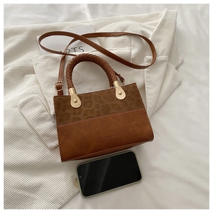 Detail of a brown leopard print patchwork handbag with gold hardware and brand logo