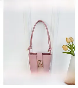 Close-up of pink bucket bag showing leather texture and gold logo metal buckle