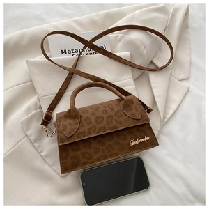 Détail du sac bandoulière imprimé léopard avec logo doré à côté d'un smartphone