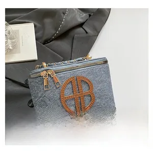 Detail of light blue box bag featuring gold chain strap and large round logo patch