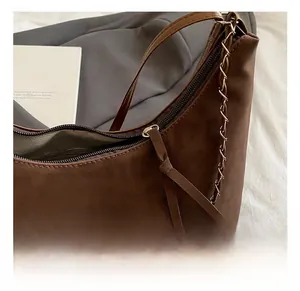 Close-up of the fine silver metal chain and stitching on this dark brown leather tote bag
