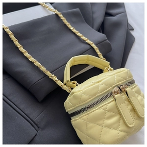 Detail of yellow quilted leather mini bucket bag with gold chain strap and dual zippers