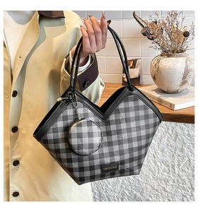 Detail of grey plaid tote bag featuring a V-shaped opening and a round coin purse charm