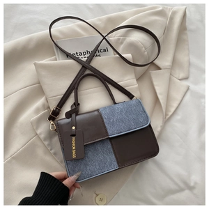 Detail of color-block crossbody bag with brown leather, blue fabric, and fashion tag