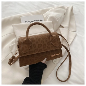 Détail du sac léopard avec logo doré sur costume blanc et livre en arrière-plan