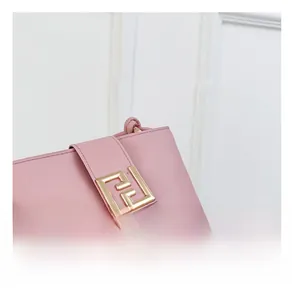 Detailed macro view of pink leather bucket bag featuring a polished gold geometric buckle