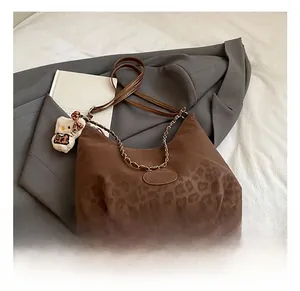 Detail of leopard print tote bag with gold chain strap and cute plush charm on blazer