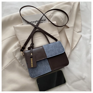 Close-up of contrast color patchwork square bag on white suit with fashion tag detail